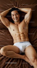Smiling fit man relaxing in white underwear on bed