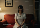Happy Young Woman Sitting on Couch in Cozy Living Room