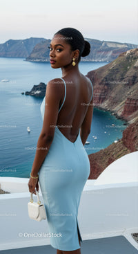 Elegant woman in light blue dress overlooking sea cliffs