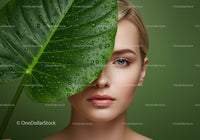 Close-Up of Woman with Blue Eyes and Green Leaf Covered in Water Droplets