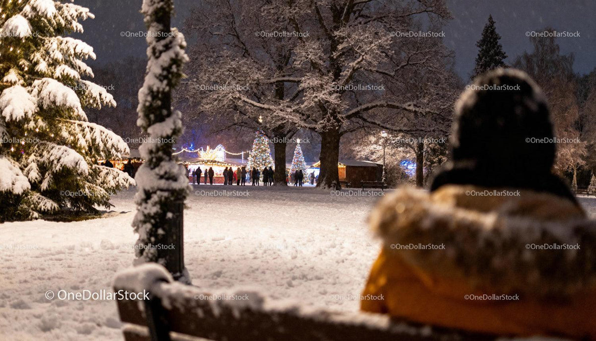 Person enjoying snowy park view of Christmas market lights