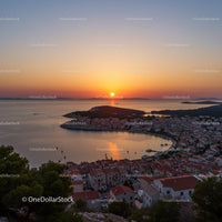 Serene Sunset Over Coastal Town with Red Rooftops and Boats