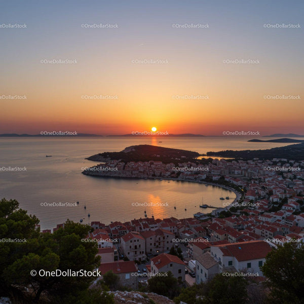 Serene Sunset Over Coastal Town with Red Rooftops and Boats