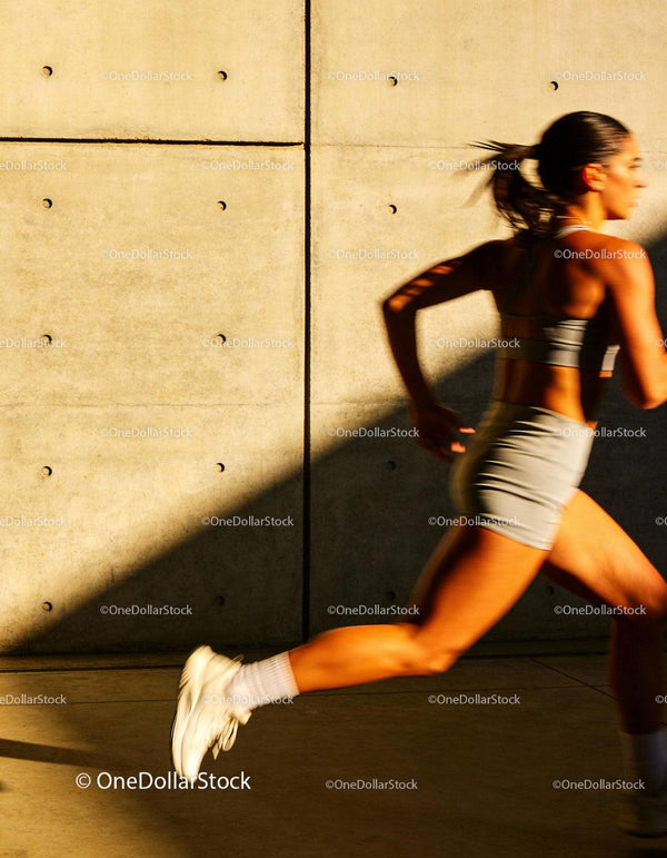Active woman sprinting outdoors in sunny evening light