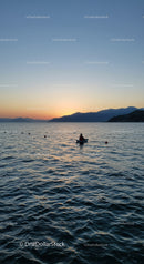 Serene Sunset Over Calm Sea with Mountain Silhouette and Boat