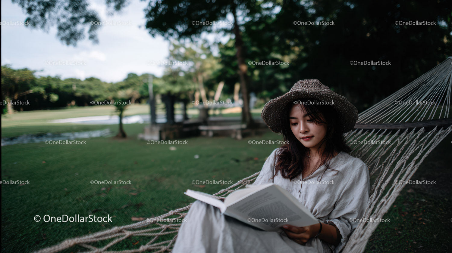 Young Woman Relaxing in Hammock Reading Book in Green Park
