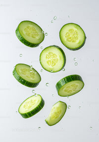Fresh cucumber slices suspended in clear water droplets