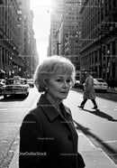 Elderly Woman in Busy City Street Surrounded by Vintage Cars