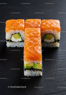 Fresh salmon sushi rolls with avocado on black slate