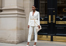 Elegant woman in white suit standing by classic doors