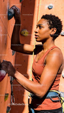Focused woman climbing on indoor rock wall with safety rope