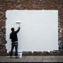 Man Painting Over Graffiti on Urban Brick Wall