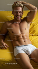 Smiling young man relaxing on yellow bed with white shorts