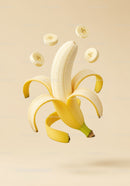 Peeled banana with floating banana slices on beige background