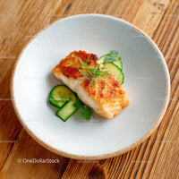 Fresh Grilled Fish Fillet with Cucumber Garnish on White Ceramic Plate