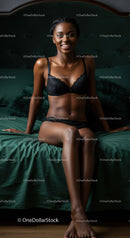Smiling woman in black lingerie sitting on green bed
