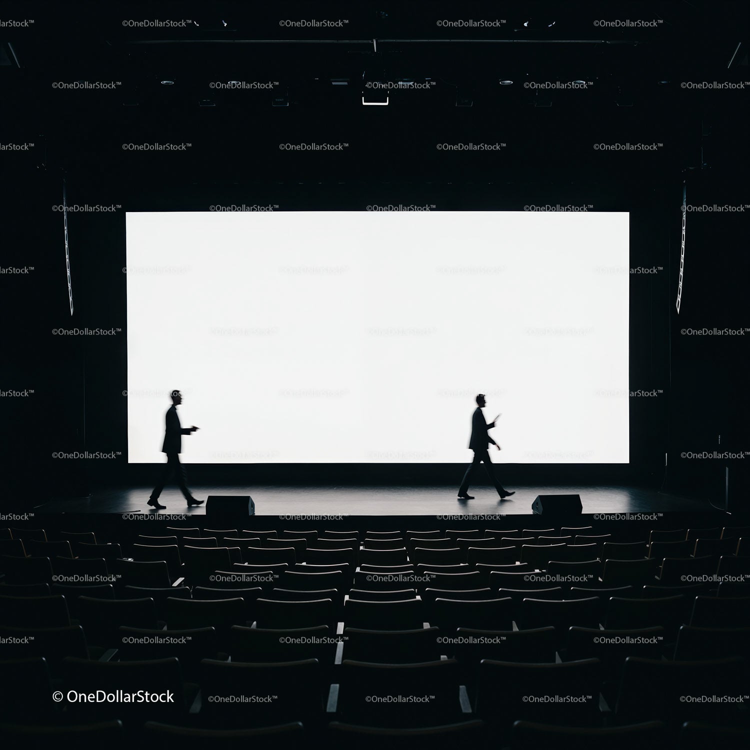 Silhouettes of Speakers Crossing Stage in Dark Auditorium