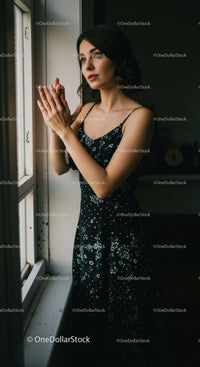 Young woman standing by window in thoughtful moment