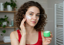 Young Woman Applying Face Cream with Skincare Products in Bathroom