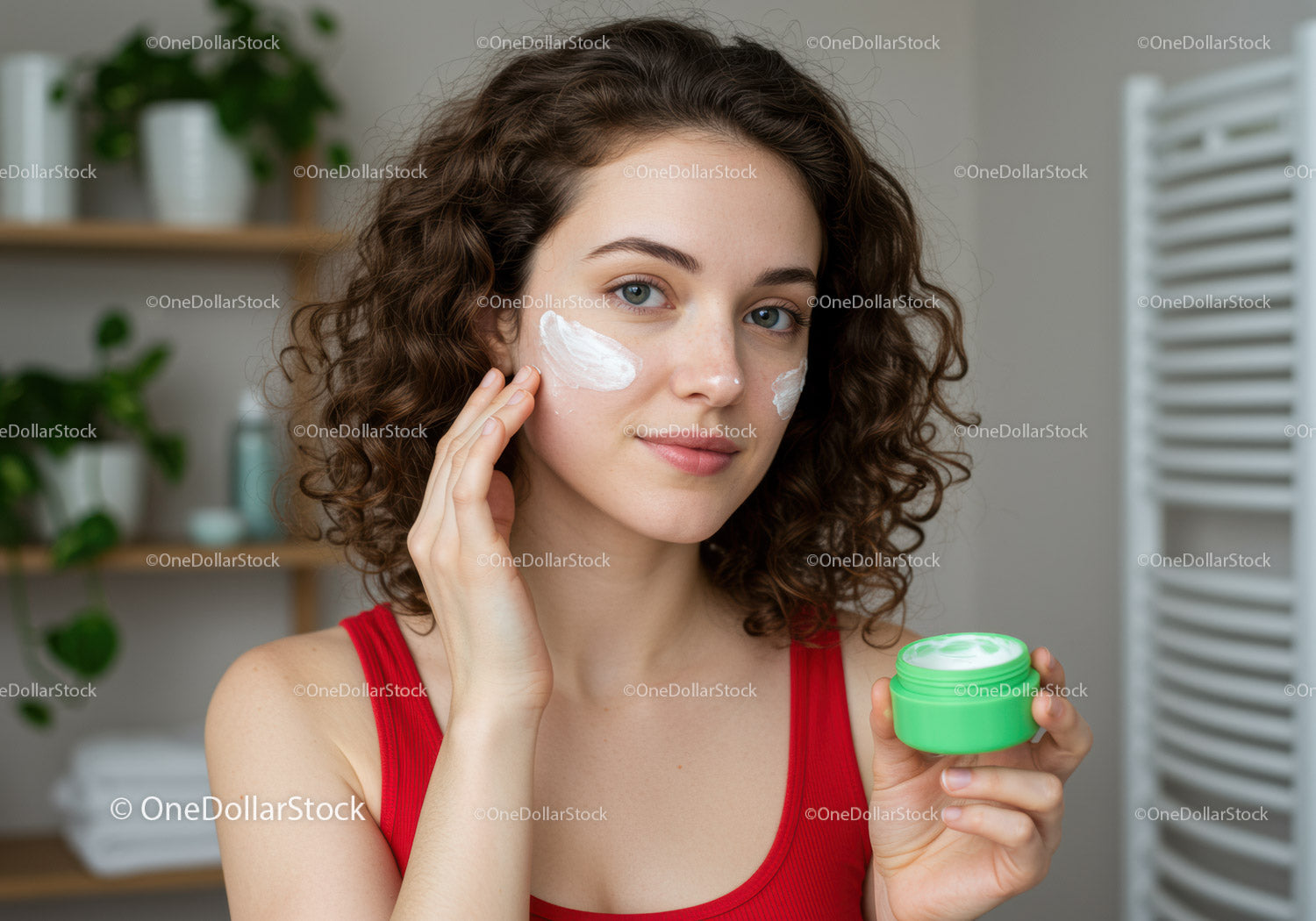 Young Woman Applying Face Cream with Skincare Products in Bathroom