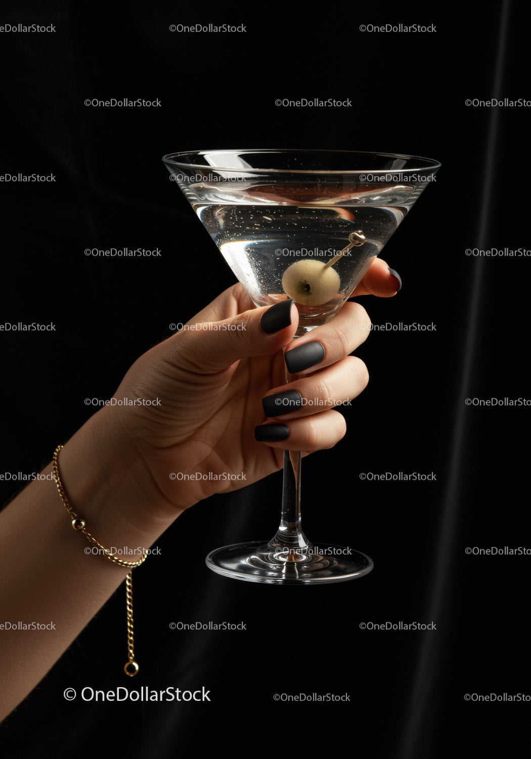 Hand Holding Martini Glass with Olive on Black Background