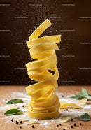 Twisted tagliatelle pasta with flour and herbs on wood