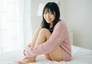 Young Woman Relaxing in Pink Sweater Sitting on Bed in Bright Room
