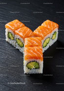 Fresh salmon avocado sushi rolls on dark surface