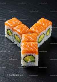 Fresh salmon avocado sushi rolls on dark surface