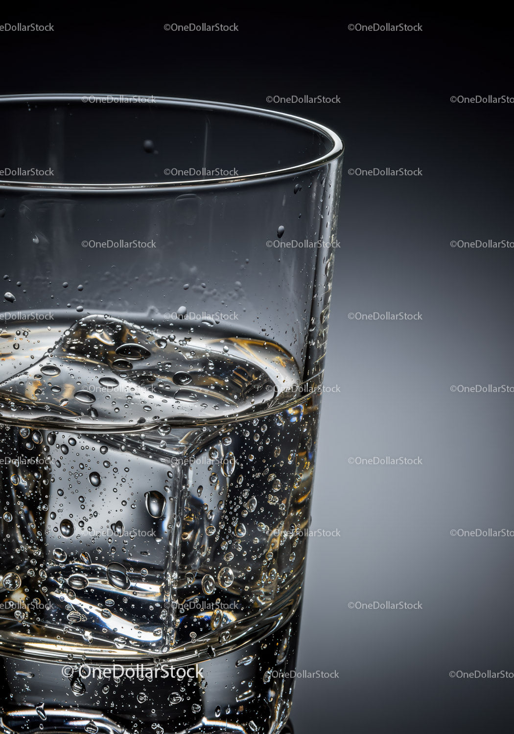 Clear glass of sparkling water with ice cubes closeup