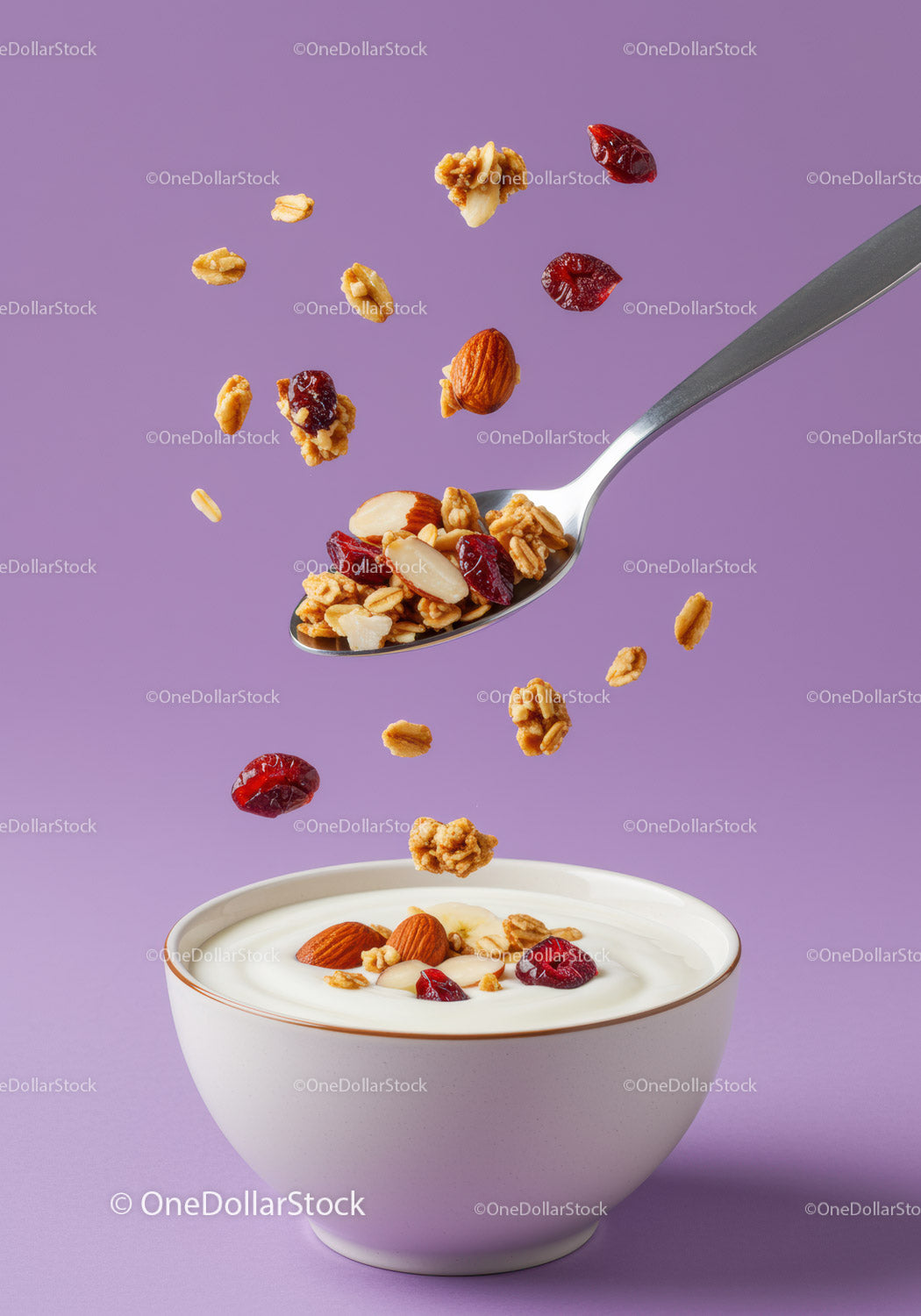 Granola i orzechy wpadające do miski z kremowym jogurtem