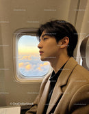 Thoughtful young man gazing outside airplane window