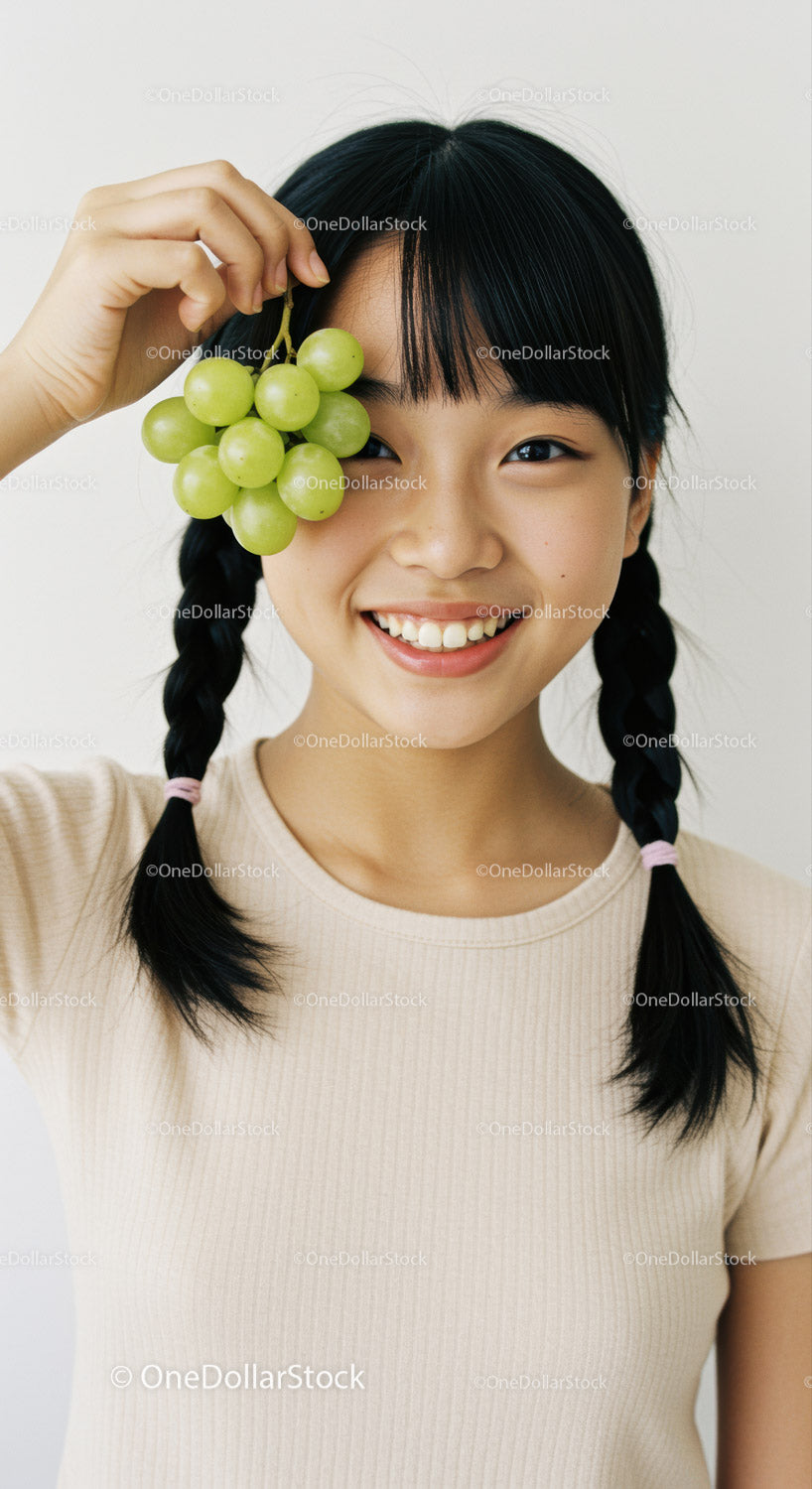 Young Woman with Braided Hair Enjoying Fresh Green Grapes in Bright Indoor Setting