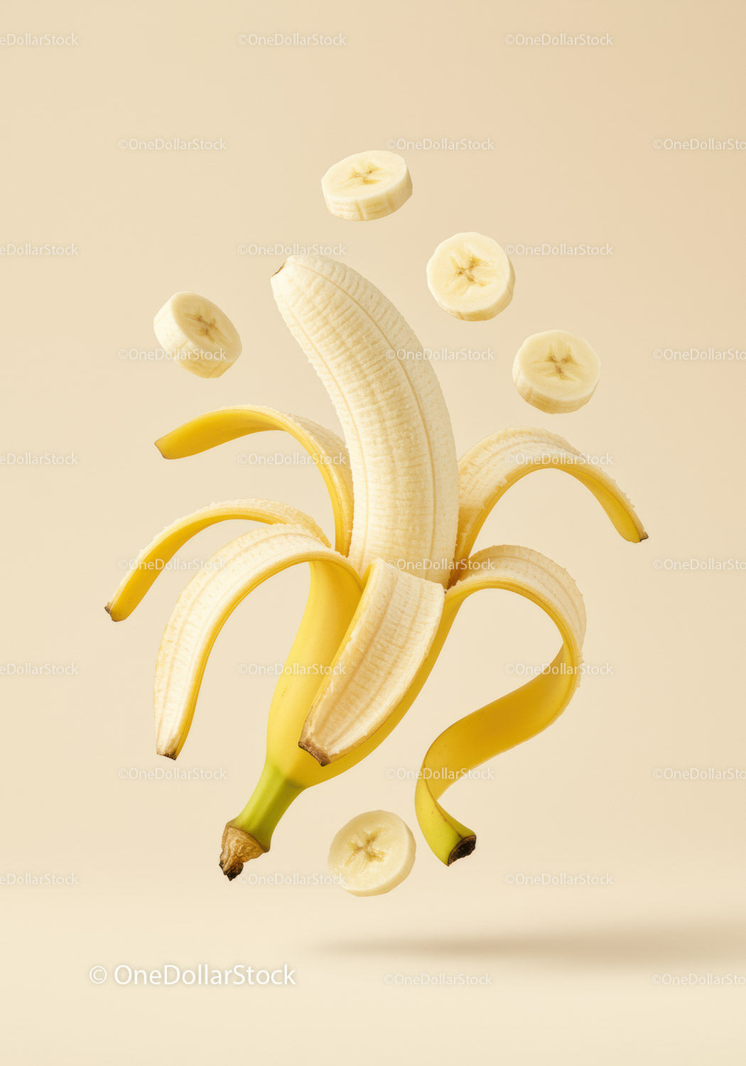 Peeled banana with floating slices on beige background