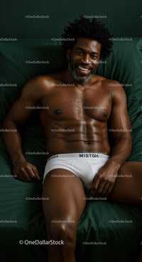 Smiling man relaxing on dark green bedding in white underwear