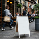 Blank sidewalk sign on busy urban cafe street