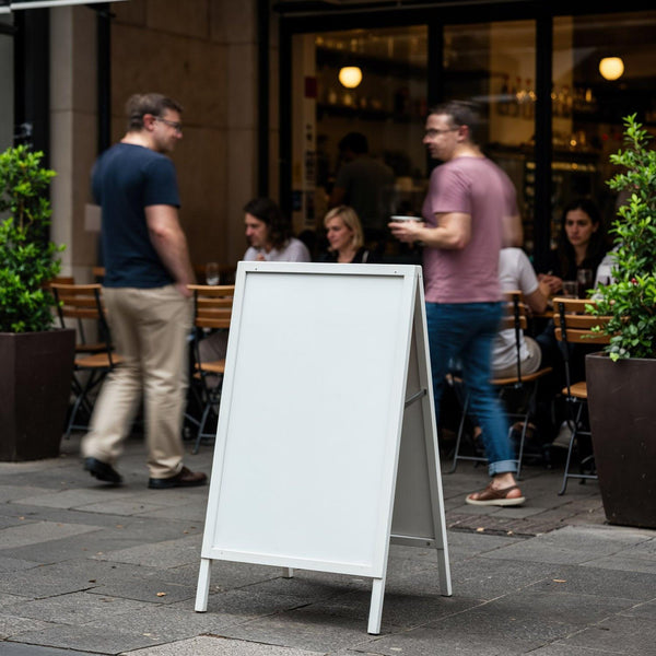 Blank sidewalk sign outside busy urban cafe JPG Mockup Image