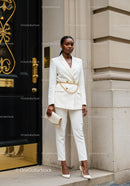 Elegant woman in white suit standing by ornate door