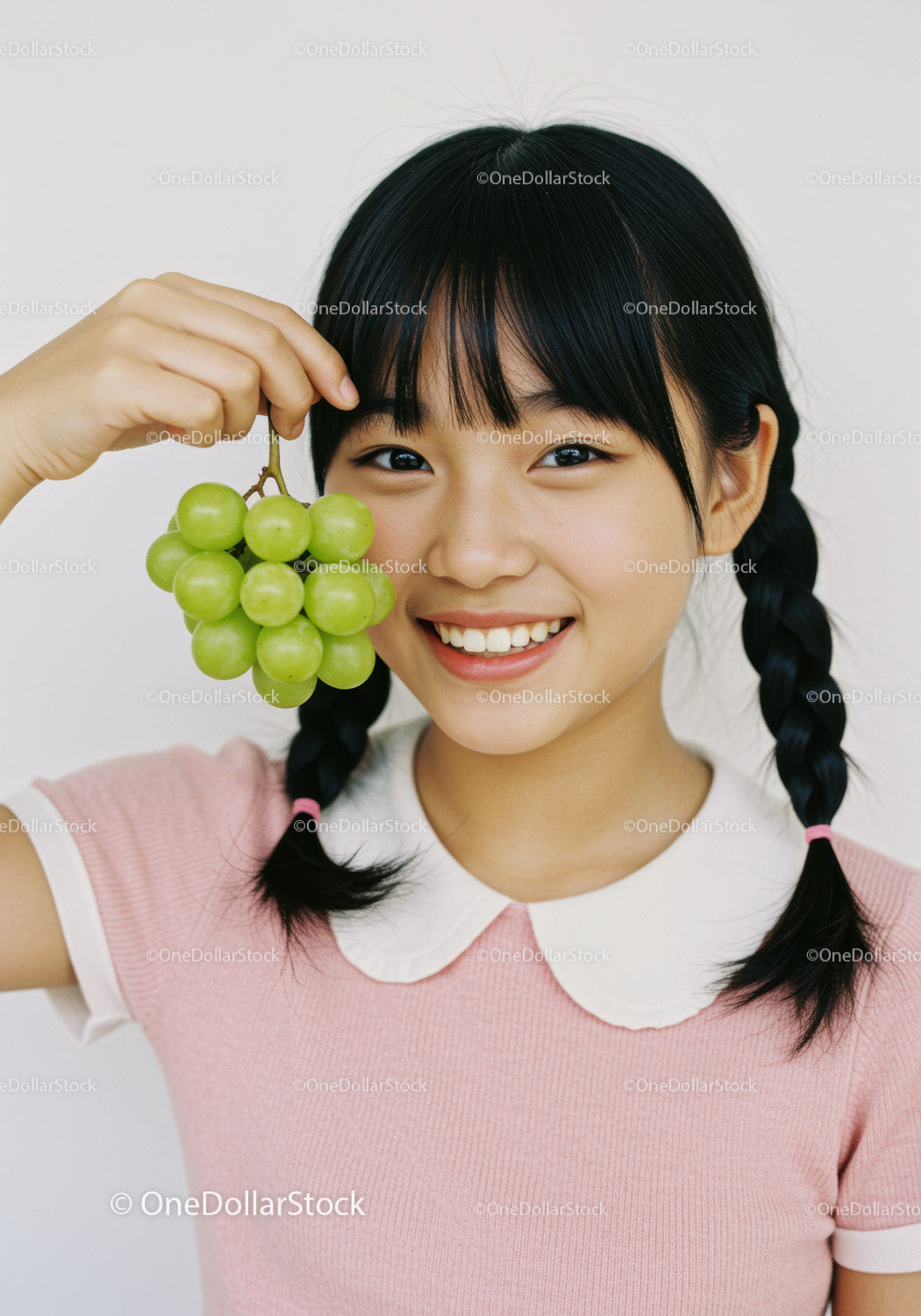 Cheerful Girl Holding Green Grapes Smiling in Bright Casual Outfit