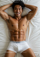 Smiling muscular man relaxing on white bed in underwear