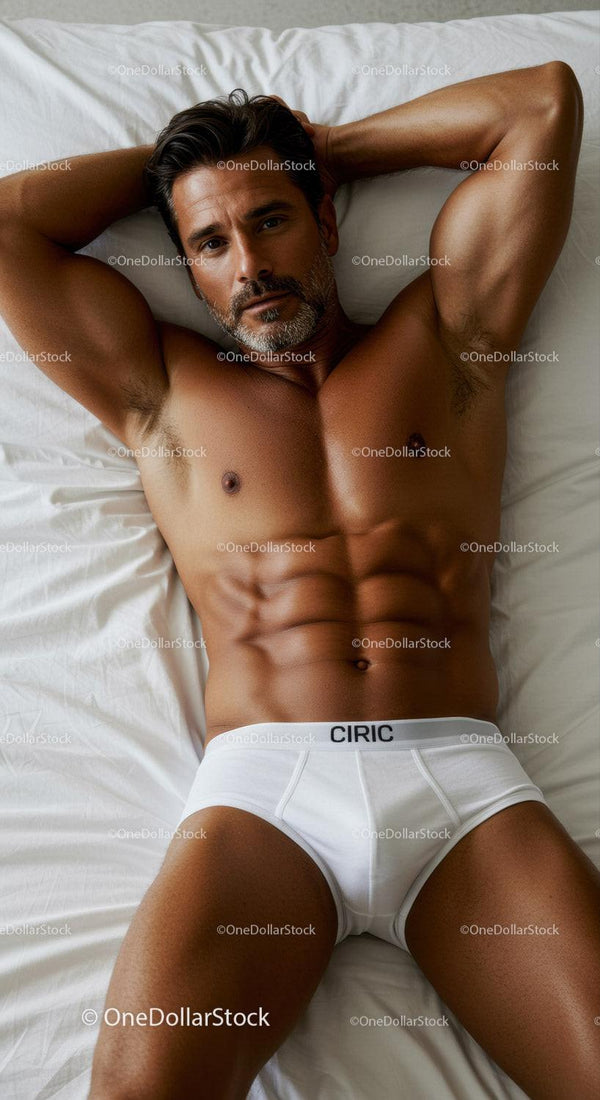 Athletic man relaxing on bed in white briefs