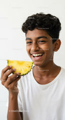 Young Boy Enjoying Fresh Pineapple Slice in Bright Studio