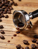 Fresh espresso dripping from portafilter on wooden table
