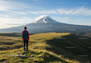 Majestic Snow-Capped Volcano Behind Rolling Green Hills with Hiker