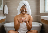 Happy Woman with Mud Face Mask Sitting in Bathtub in Bathroom