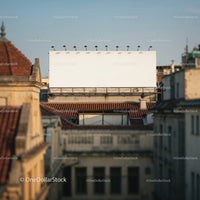 Empty billboard over city rooftops at golden hour