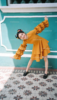 Joyful woman in mustard dress posing against turquoise wall