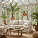 Woman arranging white sofa in bright cozy sunroom