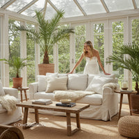 Woman arranging white sofa in bright cozy sunroom
