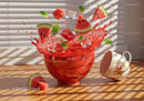 Fresh watermelon pieces splashing juice in red bowl